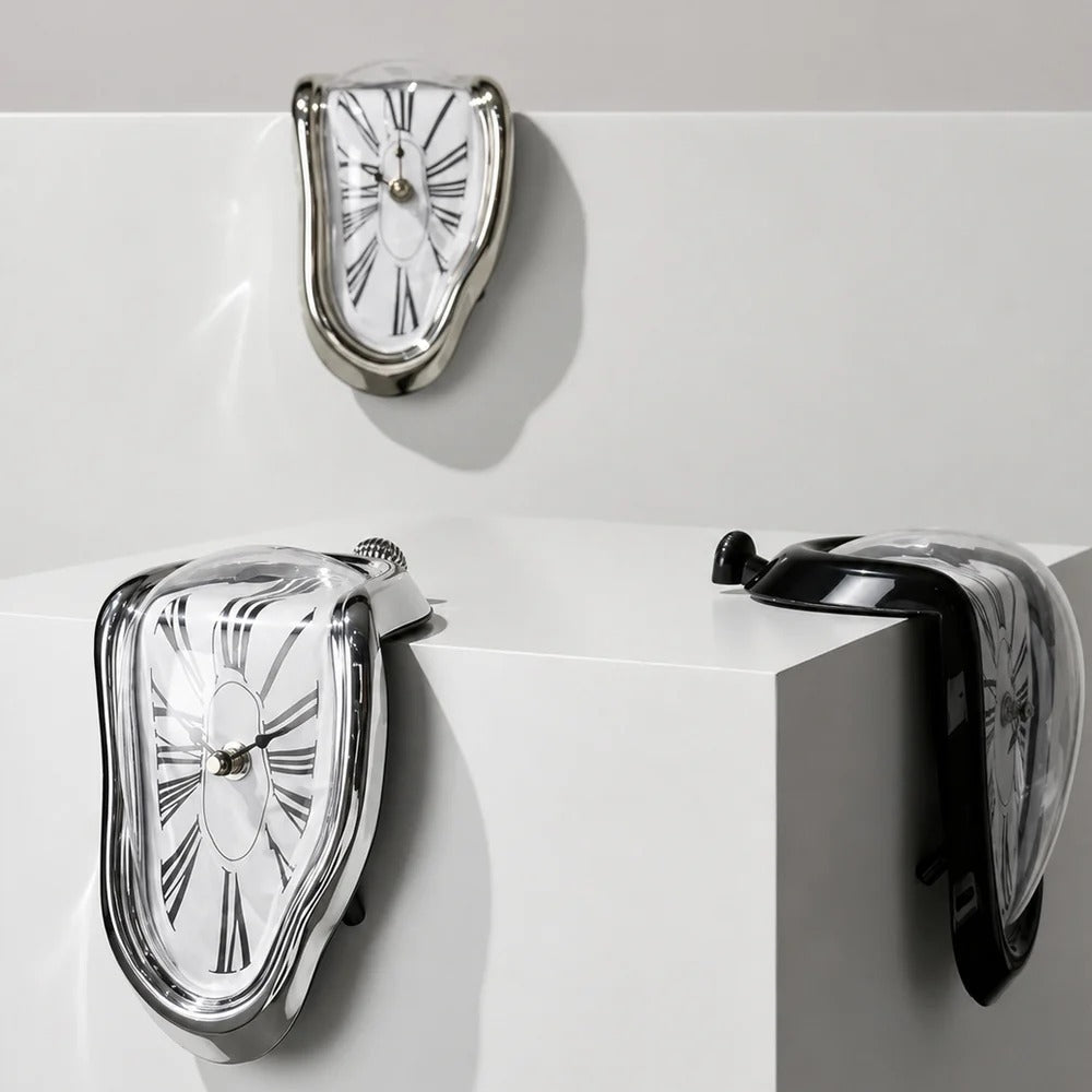 Three melting clocks in silver and black draped over the corners and edges of white plinths in a studio, each sagging differently according to the edge it rests on